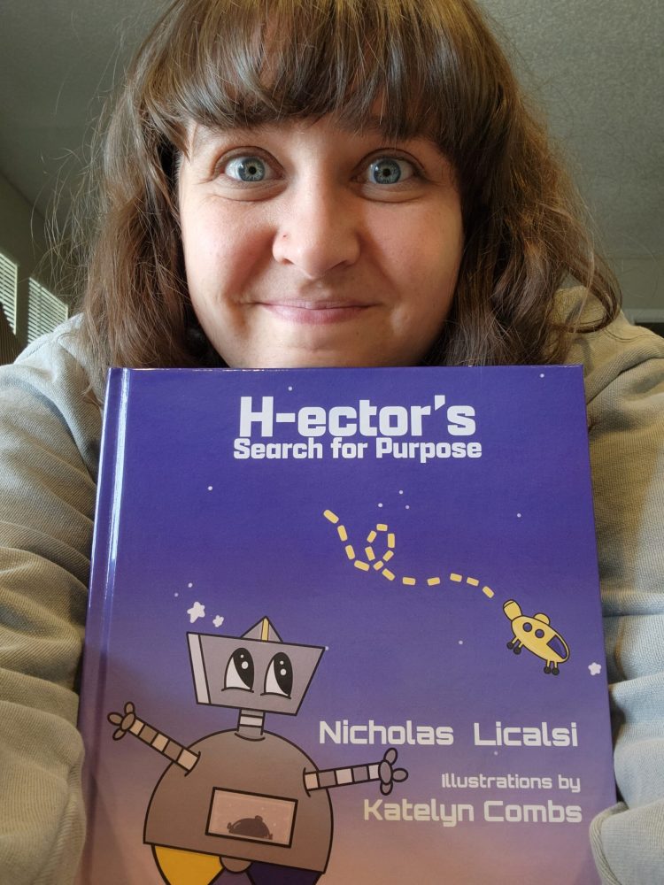 Katelyn Combs holding the book H-ector's Search for Purpose